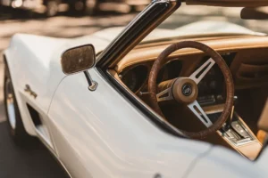 Close-up of a restored vintage convertible showing detailed steering wheel, dash, and door alignment during exterior and interior refinishing.