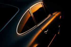 Elegant rear-side view of a vintage car with a smooth reflective surface and rich lighting, emphasizing high-quality refinishing and surface restoration.