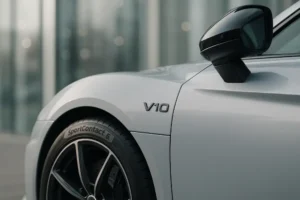 Close-up view of a sleek silver car's front fender and side mirror showing detailed paintwork and precision alignment after vehicle restoration.