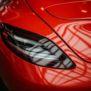 Close-up of a freshly refinished red car panel with seamless paintwork and taillight detailing, showcasing premium surface restoration and reflective clarity.